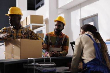 Posta tasnif merkezi Afro-Amerikan işçi takımı teslimat için paket hazırlıyor. Posta hizmetleri çalışanları, postanenin deposundaki kasada bir paket bulmuşlar.