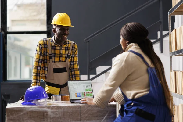 Retail storehouse employees using customer purchase list on laptop to fulfill client order and prepare parcel for delivery. African american warehouse workers checking buyers checklist on computer