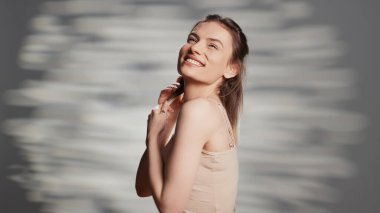 Beautiful woman embracing imperfections with bare skin, posing with natural look on camera. Smiling confident model creating empowering and uplifting beauty campaign, elegance.