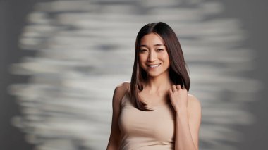 Smiling glowing girl posing with luminous skin on camera, feeling confident embracing imperfections. Young woman with radiant appearance promoting self love and bodycare campaign.