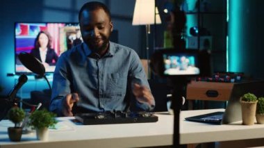 BIPOC içerik yaratıcısı, yeni çıkan DJ denetleyicisinin teknoloji değerlendirmesini kaydediyor, paketleri açıyor ve izleyicilere özelliklerini sunuyor. Hayranlara ses karıştırıcı gösteren bir etken