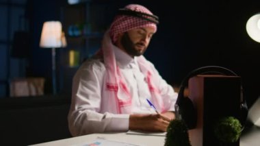 Uzaktan kumandalı gülümseyen bir tele-işçinin portresi, rahat, şık bir dairede kağıt üzerinde yazıyor. Memleketteki çalışanlar bilgileri çapraz eşleştiriyor, laptoptan nota veri kopyalıyor