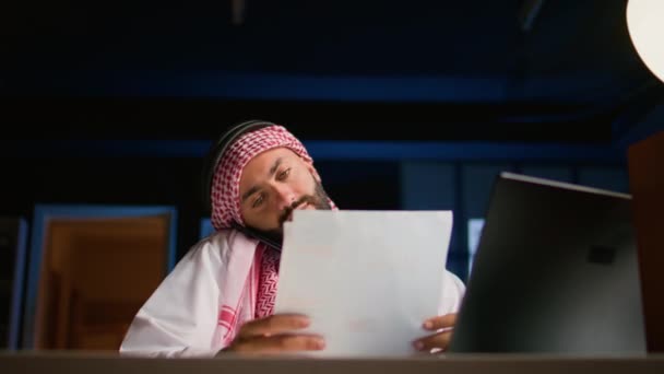 Trabajador Musulmán Contestando Una Llamada Telefónica Mientras Trabaja Remotamente Desde — Vídeo de stock