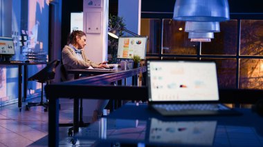 Business woman talking on landline phone at work, answering office telephone call to solve financial investment. Entrepreneur using phone line at corporate job, after hours. Handheld shot.