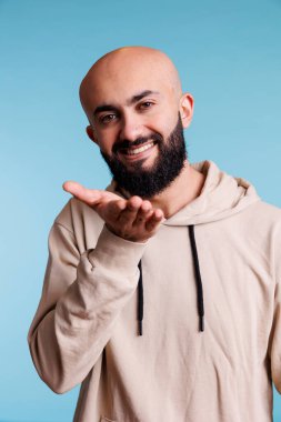 Neşeli bir yüz ifadesiyle kameraya bakarken gülümseyen Arap adam hava öpücüğü veriyor. Sevgisini ifade eden ve neşeli duygular gösteren mutlu bir insan stüdyo portresi.