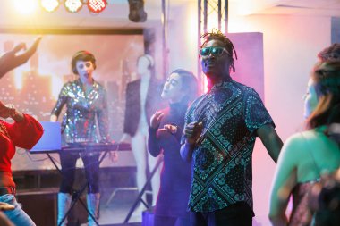 Gençler gece kulübünde dans ediyor ve diskotek partisinden zevk alıyorlar. Yetişkinler kulüpte eğlenirken dans pistinde sahne ışıklarıyla elektronik müzik eşliğinde enerjik hareketler yapıyorlar.