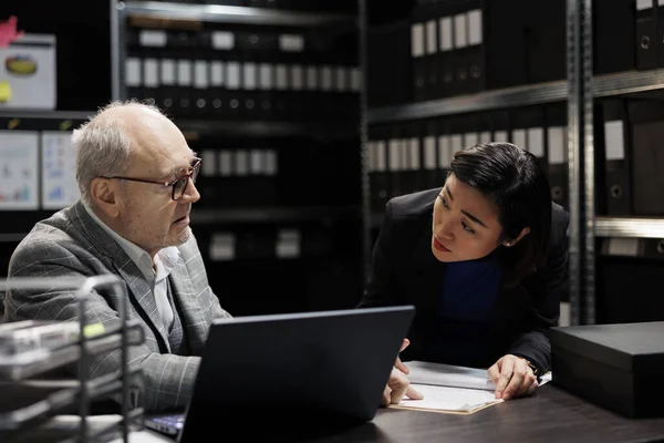 Business management coworking executives discussing accountancy market database information. Analysis paperwork in archival file room filled with folders on cabinet shelves and graphic charts