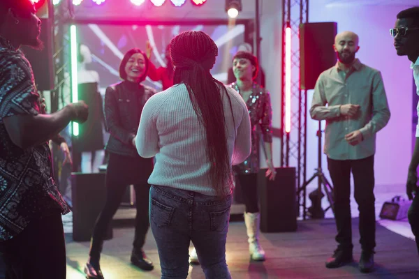 People laughing and dancing together while partying in nightclub. Diverse clubbers crowd enjoying music and having fun on dancefloor while attending entertainment event in club