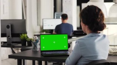 İş kadını, birlikte çalışma alanındaki boş renkli ekrana bakarak, yeşil ekranla dizüstü bilgisayarda çalışıyor. Tecrit edilmiş model şablonu ve ticaret görevleriyle bilgisayar ekranını inceleyen genç bir yetişkin. El kamerasıyla..