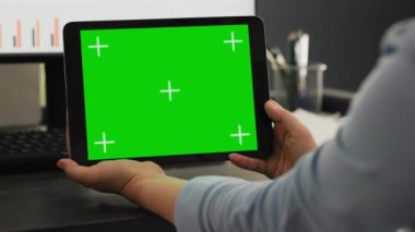 İşçi, ajansla birlikte çalışan uzay ofisindeki tablette yeşil ekranı inceliyor, mobil cihazda izole edilmiş telif alanı olan kromakey ekrana bakıyor. Çalışanların elinde kromakey aygıtı var.
