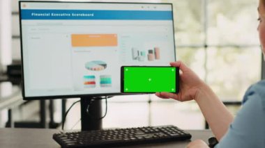 İş kadını, başlangıçta iş yerinde yeşil ekran şablonu olan akıllı telefon uygulamasını analiz ediyor. İzole edilmiş krom anahtar görüntüsüne bakan kişi dijital mobil aygıt, kopyalanmış uzay.