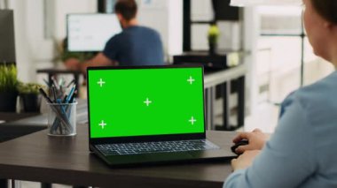 Şirket uzmanı yeşil ekran şablonlu dizüstü bilgisayar kullanıyor. Bilgisayarda model kromakey ekran üzerinde çalışıyor. Ekranda izole edilmiş telif alanı düzenini analiz eden kadın, ofis masasında çalışıyor..