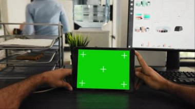 Yöneticinin POV 'u yeşil ekran şablonu ile tablet kullanır, kromakey düzenine bakar ve birlikte çalışma alanında oturur. Cihaz ekranında boş kopyalama alanını inceleyen genç adam.