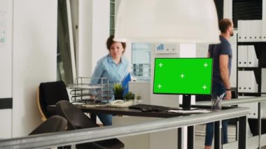 İş operasyonlarını çözen insanlarla birlikte çalışma alanındaki bilgisayarda yeşil ekran düzeni olan boş bir masa. İzole edilmiş kopyalama alanı görüntüsü olan bilgisayarı gösteren çalışma istasyonu.
