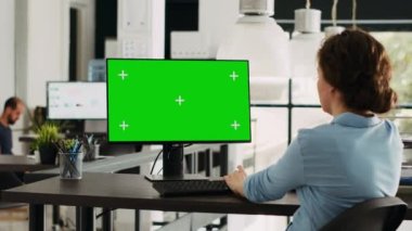 Çalışma istasyonundaki bilgisayarda yeşil ekran görüntüsünü kullanan başlangıç yöneticisi, izole edilmiş telif alanı şablonu ile modern ağı kontrol ediyor. Model renkli ekran ile çalışan iş kadını.