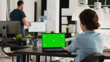İş kadını dizüstü bilgisayardaki yeşil ekrana bakar, masadaki bilgisayarı kontrol eder ve başlangıç işlemleri üzerinde çalışır. Bilgisayarda izole edilmiş kromakey şablonu kullanan çalışan, kopyalanmış uzay görüntüsü.