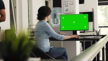 Ofis çalışanı masadaki yeşil ekran monitörünü kontrol ediyor, bilgisayar masaüstündeki boş telif alanı şablonuyla iş operasyonları üzerinde çalışıyor. Kişi yazma bilgisi ve izole edilmiş modelleme inceleniyor.