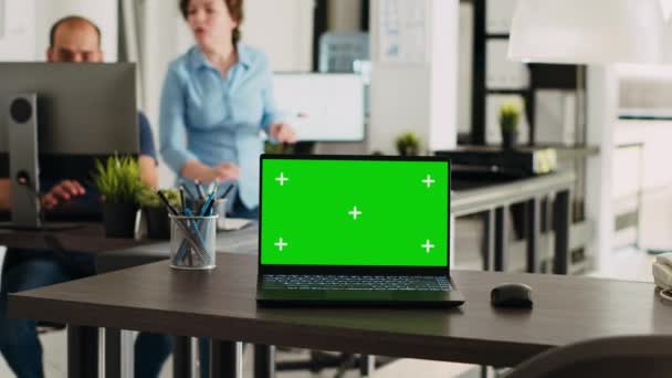 绿屏笔记本电脑放置在空荡荡的写字台上 开放式平面图上有独立显示的办公场所 可移动计算机在软件上运行空白色键布局 — 图库视频影像