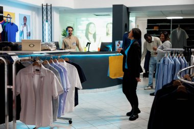 Alışveriş torbaları tutan ve giyim mağazasındaki kasiyere gülümseyen memnun müşteri. Neşeli gülümseyen Asyalı kadın kağıt paketler taşıyor, butikte duruyor.