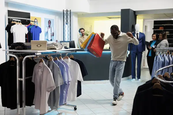 兴奋的非洲裔美国购物狂 背着购物袋 在服装店跳舞 时尚精品店快乐快乐的客户手握服装包 玩得很开心 — 图库照片