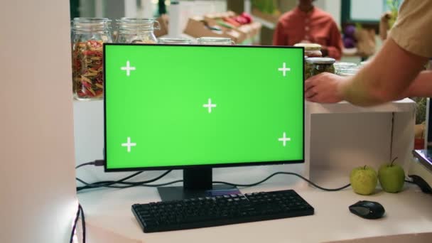 レジスタでの販売者はコンピュータでグリーンスクリーンを使用し Pcモニターで隔離されたコピースペースディスプレイを表示します 若い男中小企業のオーナーは 空白の染色体で健康的なライフスタイルを奨励しています — ストック動画