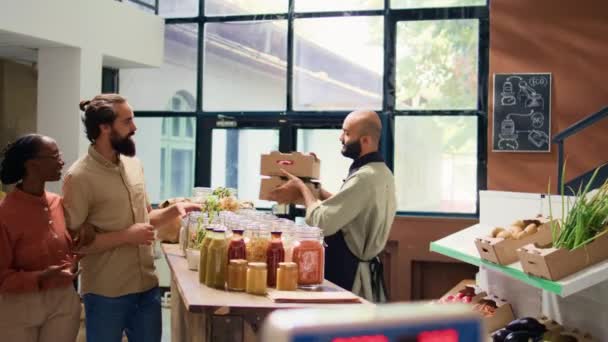 夫妇支持当地商人 购买生态新鲜收获的水果和蔬菜 在零废物超市寻找自然物品 小企业主用样品向买主致意 — 图库视频影像