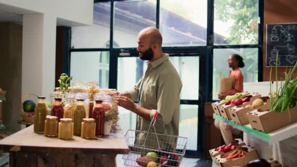 地元の食料品店で新鮮な食材を購入するエコ意識のある人は 農薬や添加物フリー製品を探しています スパイスで棚を調べる中東のクライアント — ストック動画