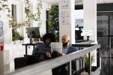 Arap girişimciler iş stratejilerini gözden geçirir ve istatistik çizelgeleriyle belgeleri analiz ederler. Şirket çalışanları analitik raporlarını şirket iş birliği ofisinde kontrol ediyorlar.