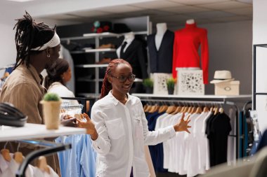 Giyim mağazası sahibi nüfuz sahibi ile konuşuyor ve reklam yapmak için giyim kuşamını stoklarda gösteriyor. Alışveriş merkezi çalışanı moda blogcusu ile sohbet ediyor ve tanıtım için kıyafet sergiliyor.