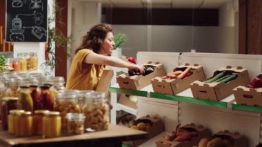 Sıfır atık süpermarketinde organik sebze almak için kağıt torba kullanan bir kadın. Tek kullanımlık plastik poliçesi olmayan çevre dostu mahalle mağazasından müşteri alışverişi