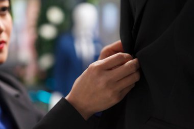 Alışveriş merkezindeki butik kadın, giyim mağazasını kapatırken ceket düğmelerini bağlıyor. Giyim mağazası galerisi silah satıcısı. Satılık giysiler.