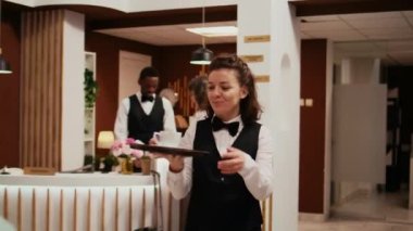 Otel kapıcısı, müşterilere kahve servisi yapıyor. Dinlenme odasında kitap okuyor. Kapsamlı tatil yerlerinde harika hizmetler sunuyor. Kanepede oturan yaşlı adam için rahatlama garantisi veren kadın çalışan..