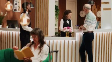 Neşeli personel, otel lobisinde kıdemli bir adama yardım ediyor, kontrol edildikten sonra giriş kartı alıyor. Bellboy yedek odaya bavul taşıyor, konsiyerj hizmeti veriyor. Üçayak atışı.
