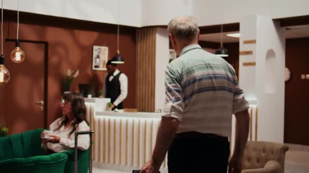 Starszy Mężczyzna Wchodzący Hotelowego Lobby Bagażem Proszący Usługi Konsjerża Odprawy — Wideo stockowe