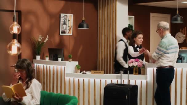 Θυρωρός Του Ξενοδοχείου Εξετάζει Διαβατήριο Για Συμπληρώσει Έντυπα Στη Ρεσεψιόν — Αρχείο Βίντεο