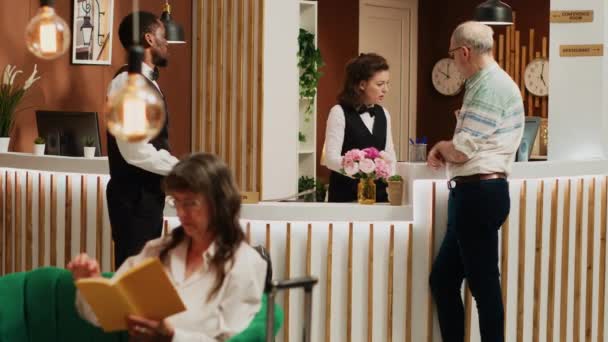 Radosny Personel Pomaga Starszemu Człowiekowi Hotelowym Lobby Otrzymując Kartę Dostępu — Wideo stockowe