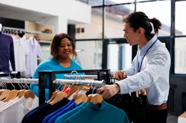 Gündelik kıyafetlere bakan Afrikalı Amerikalı müşteriler modern butikte şık ürünler satın alıyorlar. Alışverişkolik kadın yeni bir gardırop istiyor, giyim mağazasından şık kıyafetler alıyor.
