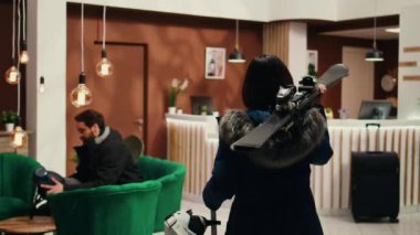 Asyalı biri, dağ otelinde kayak resepsiyonistinden mevsimlik sporun tadını çıkarmak için kış pansiyonuna gelmesini istedi. Kar kayağı ekipmanı ve kask taşıyan bir kadın yolcu..