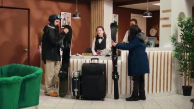 Turist çiftler resepsiyona gelerek dağ yamaçları ve rezervasyonlarda yer alan kayak hizmetleri hakkında konuşuyorlar. Çeşitli çalışanlar kış sporu meraklılarını teçhizatla selamlıyor.