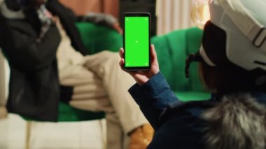 Bir kişi yeşil ekranlı akıllı telefon kullanır ve erkek arkadaşıyla keyifli sohbetler yapar, telefonda boş krom anahtar görüntüsü gösterir. Kış boyunca Alp disiplini kayak merkezinde çeşitli çiftler.
