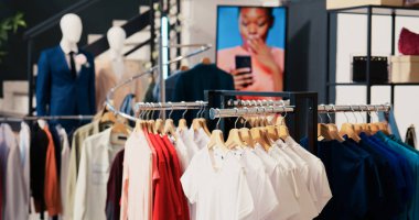 Alışveriş merkezindeki boş giyim mağazası, raflarda yeni moda koleksiyonu. Askılarda ve raflarda şık kıyafetler, müşteriler için eşya ve aksesuarlarla dolu modern bir butik.