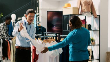 Afrika kökenli Amerikalı müşteriler günlük kıyafet alışverişi yapıyor, butik müdürüyle kıyafet malzemelerini tartışıyorlar. Alışverişkolik kadın giyim mağazasından şık kıyafetler alıyor. Moda konsepti