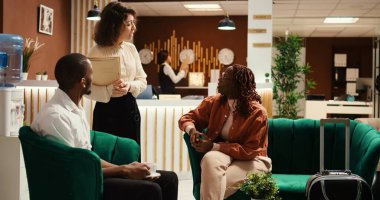 Dost canlısı, güler yüzlü otel yöneticisi turist çiftleri geri bildirim alıyor, kontrol sürecinde nerede kaldıklarını soruyor. Otel çalışanı belboy çalışanı, konukların bagajlarına yardım ediyor.