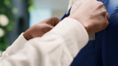Lüks moda mağazasında çalışan tam bir tezgahtar blazer ceket cebinde cep mendili ayarlıyor. Afrika kökenli Amerikalı çalışanlar, yeni moda giysi koleksiyonu sergiliyor. Manken, aşırı yakın çekim.