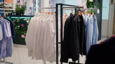 Kamera görüntüsü, üst düzey giysilerle dolu giyim mağazası koridorlarında geziniyor. Yeni açılan lüks butikte resmi kıyafet ve ceketler.