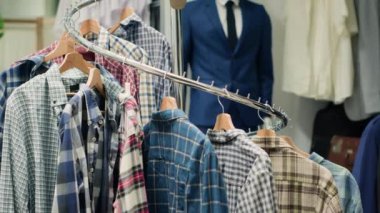 Yeni koleksiyonlarından şık ve şık kıyafetler sergilenen lüks butik elbise askılarının üzerindeki şık gömlek seçimleri. Alışveriş merkezindeki erkek gömleklerini kapat.