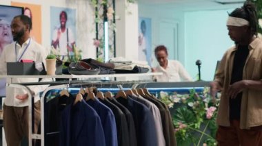 Son moda kıyafetleri ile alışveriş merkezindeki giyim mağazasından kıyafet alan müşteriler. Müşteriler modern temiz moda butiğindeki zarif erkek gömleklerine bakıyorlar.