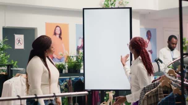 服装店的非裔美国人店主使用增强的现实屏幕向女性展示服装选择供她挑选 店员助理使用领先的显示器来帮助客户视觉化时尚选择 — 图库视频影像