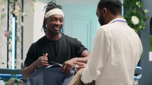 Mężczyzna Robi Zakupy Eleganckim Butiku Mody Wspomagany Przez Pomocnego Sprzedawcę — Wideo stockowe