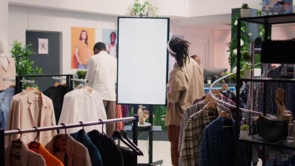 顾客在商场里使用Ar技术亭来查看便宜和可持续的服装 环保二手商店的顾客使用铅丝在衣服之间进行选择 — 图库视频影像
